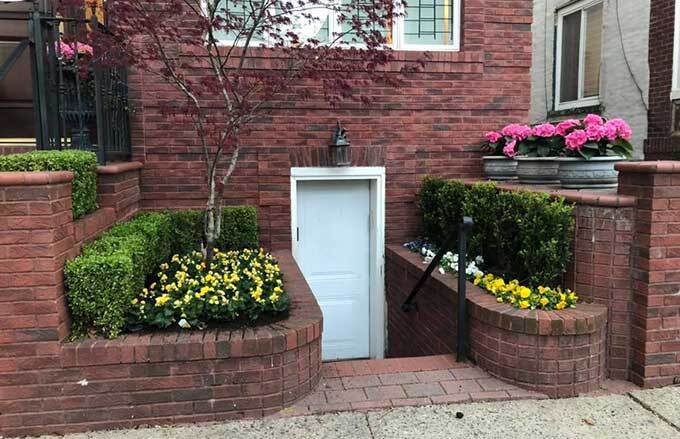 Urban row home entrance with garden beds filled with boxwood and flowers